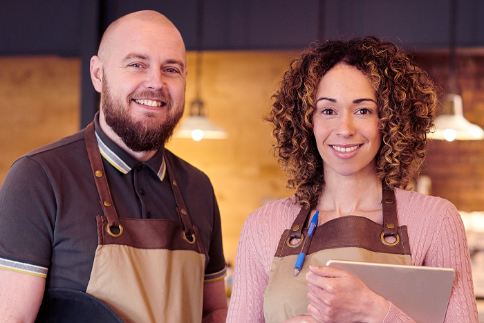 2 people in aprons with a coffee shop background