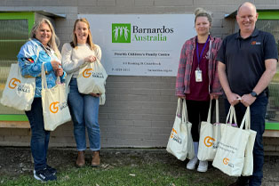 Simon and Barnados staff holding donation bags standing in front of the Barnados office sign.