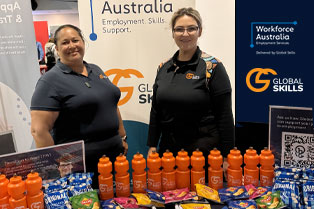 Our staff, Jennifer and Chloe, standing behind our stall table which contains branded merchandise