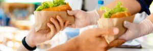 Hands from a food truck window passing salad rolls to another set of hands