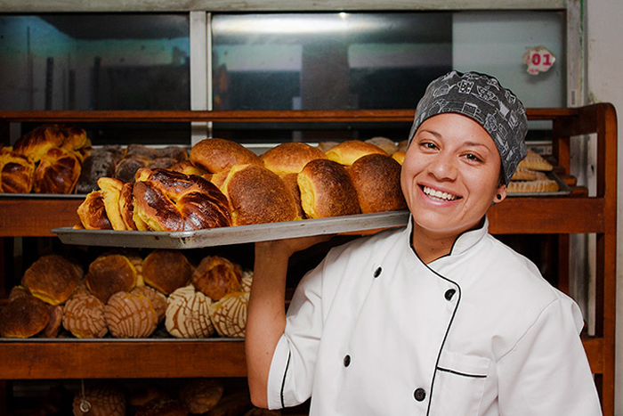 Woman carrying a tray of freshly baked bread