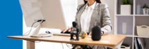 Businesswoman using a height-adjustable desk to switch between sitting and standing while working