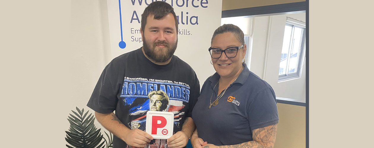 Bradley proudly holding his P plate, alongside Melissa, his Employment Consultant